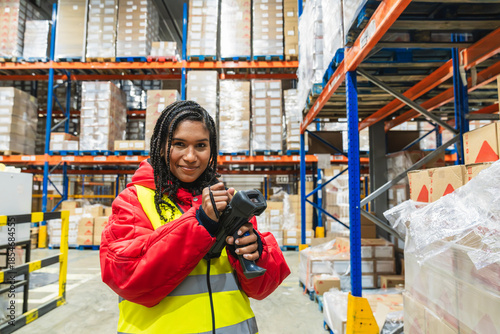 Tablou pe pânză Worker in protective clothing holding a barcode scanner, managing logistics and