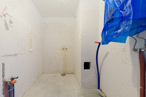 Unfinished bathroom interior with exposed pipes and wires
