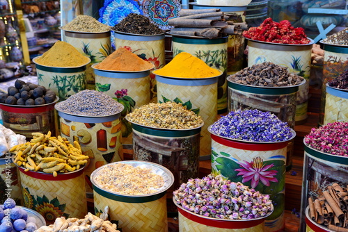 arabian spice and herb street market stall. Traditional spices market. Pots and wooden tubs stand in row with colorful tea, spices, fruits, roots, flowers. Street bazaar. Dubai, UAE.