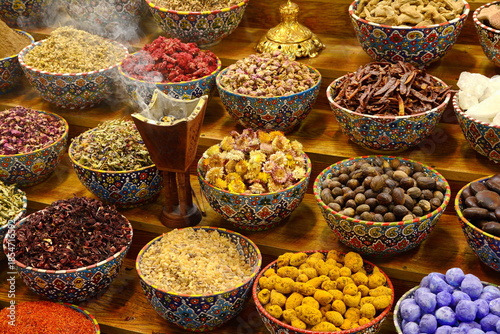 arabian spice and herb street market stall. Traditional spices market. Pots and wooden tubs stand in row with colorful tea, spices, fruits, roots, flowers. Street bazaar. Dubai, UAE.