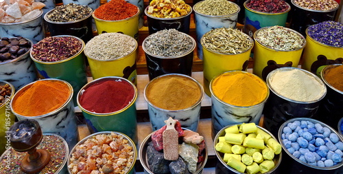 arabian spice and herb street market stall. Traditional spices market. Pots and wooden tubs stand in row with colorful tea, spices, fruits, roots, flowers. Street bazaar. Dubai, UAE.