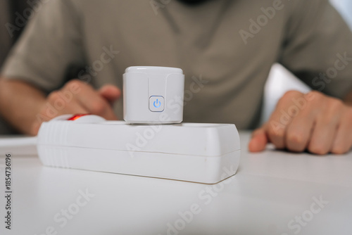 Person setting up smart home technology, connecting smart plug into power strip, demonstrating energy management, automation and remote control for modern household.