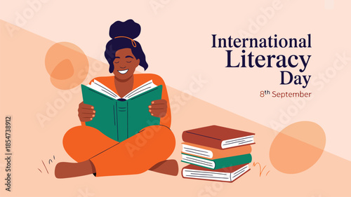 A smiling woman with dark skin sits cross legged reading a green book for International Literacy Day