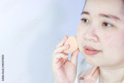 A woman is using a sponge to make her face smoother