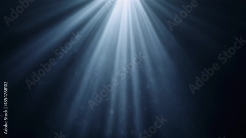 Dramatic cinematic volumetric light beams streaming down through floating dust particles in deep darkness, perfect abstract overlay background animation.