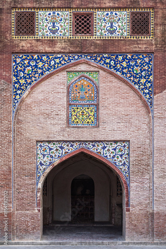 View of arch door with kashi-kari or faience tile mosaic floral and geometric decor on historic mughal Wazir Khan mosque, Lahore, Punjab, Pakistan