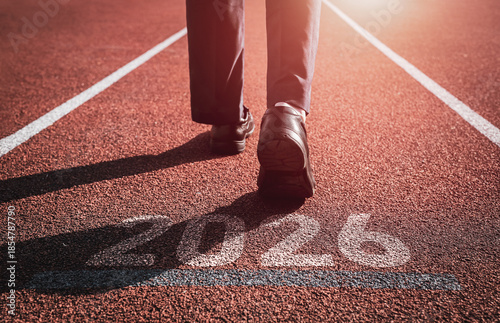 Foto Businessman walking forward with number 2026 displayed on running track