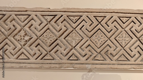 Stone architectural frieze with carved geometric pattern and ornamental details on an ancient building element. The image represents symmetry, craftsmanship, and the concept of timeless tradition