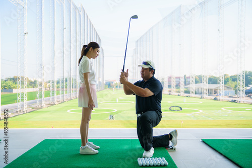 Obraz na plátně Golf instructor teaching beginner woman at driving range