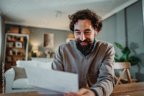 Happy man receiving good news with mail at home