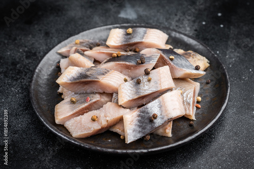 Fotografie Pickled herring chunks cured in salt and brine served with spices and herbs