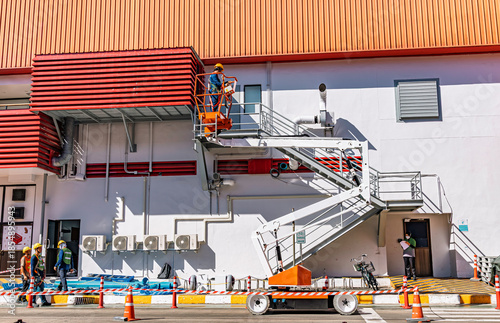 Billede på lærred Workers are working on the Orange articulate boom lift or telescopic boom lifts