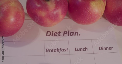 The concept of healthy nutrition in modern life. A diet plan printed on a piece of paper and a apples lying on a table