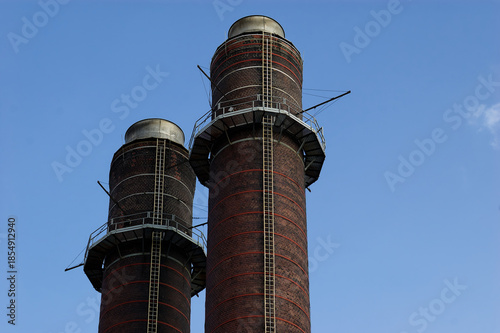 Industrial Chimneys: Tall Brick Smokestacks with Metal Platforms Standing in Outdoor Sky Vertical Shot