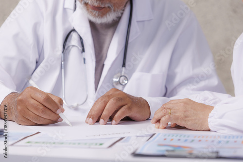 Doctor in white coat is writing on document while consulting with patient. scene conveys sense of professionalism and care in medical setting