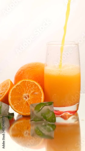 Fresh Orange Juice Being Poured into Glass with Citrus Slices
