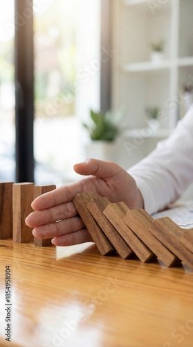 Business risk management concept with hand stopping falling wooden blocks symbolizing Crisis prevention and Strategic control, Financial stability protection, Loss prevention strategy. Vertical bg