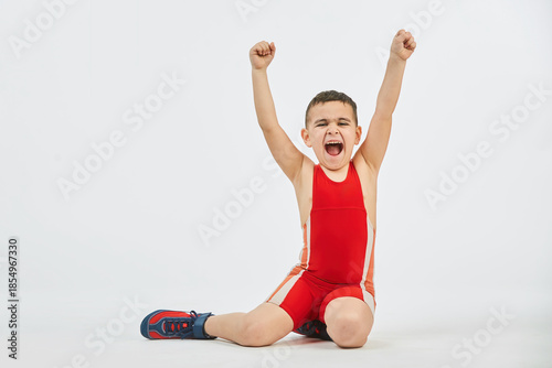 The boy is engaged in wrestling sports, dressed in a sports uniform. White background