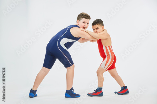 Two boys of different ages are engaged in wrestling sports. White background