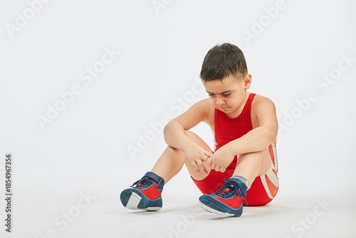 The boy is engaged in wrestling sports, dressed in a sports uniform. White background