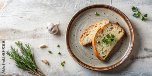Overhead View of Simple Rustic Bread Slices with Fresh Herbs and Garlic Cloves on a Plate