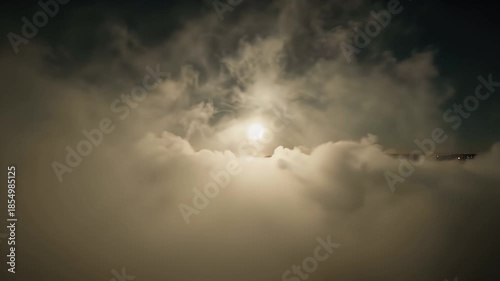 Golden Sunlight Peeking Through Dense Cloud Cover Casts Warm Glow Across a Foggy Horizon