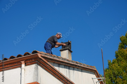 Fotografía Man repairs roof chimney on house