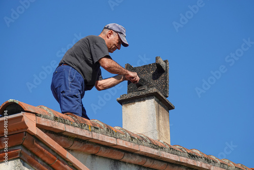 Man repairs chimney on the roof under clear sky