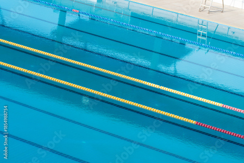 Swimming pool lanes for competition sport, perspective view of starting blocks and reflections on water.