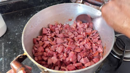 A pan on the stove frying Calabrese sausage in oil.