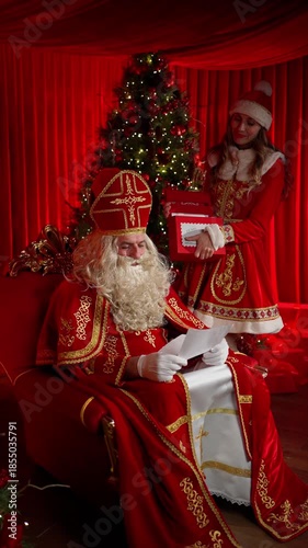 Saint Nicholas and a woman in a Santa costume read children's letters. The concept of a New Year's miracle.