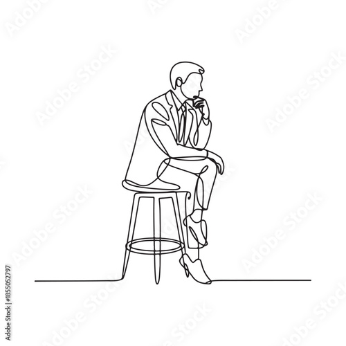 A contemplative man in a suit sits on a stool lost in thought