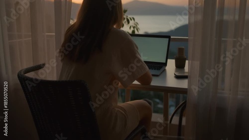 A cinematic view from a balcony workspace overlooking distant mountains or sea