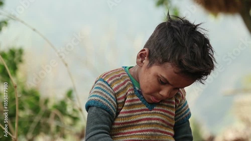 A rural Indian boy eats simple food with bread and tea while sitting outdoors in an Uttarakhand village. The scene reflects poverty, daily nutrition, childhood, and village lifestyle.