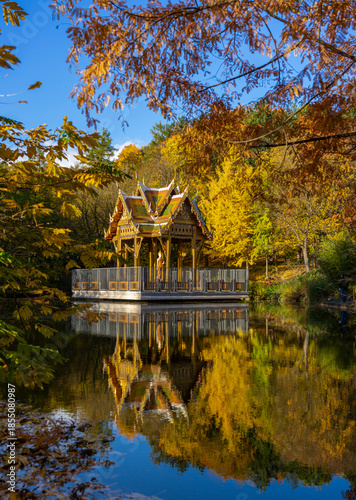 Herbst im Westpark, München: Thailändische Sala, Tempel mit Buddha Statue - farbenfrohe, bunte Bäume und Spiegelung im See