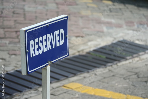 Fotografie Blue reserved parking sign placed on an urban street pavement