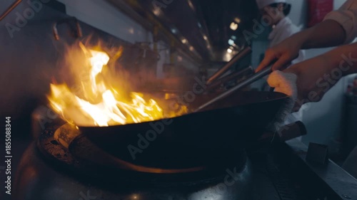 Chef Stir Frying in Professional Restaurant Kitchen Backstage with Dramatic Lighting