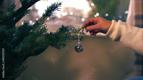 Woman decorating Christmas tree with silver bauble 