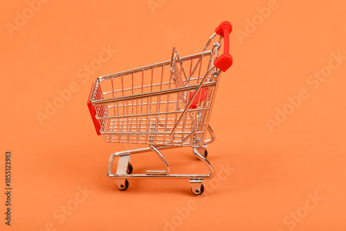 Empty shopping cart on orange background