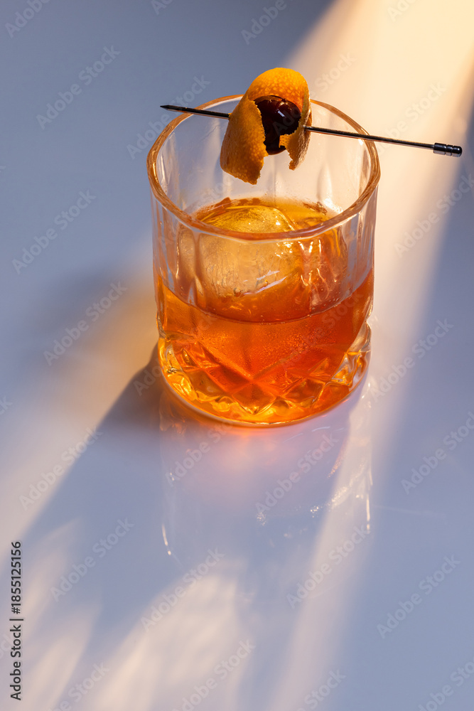 custom made wallpaper toronto digitalClose up of a manhattan cocktail served with one large ice cube on a reflective white surface with dual lighting tones and high contrast lights adding drama.