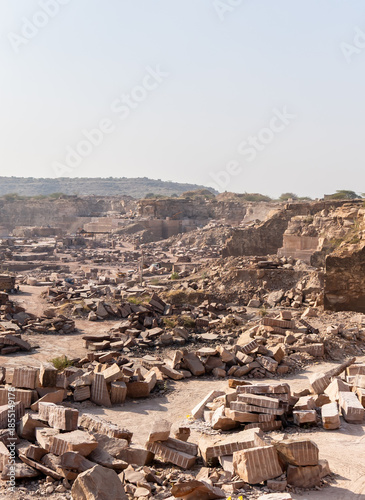 industrial landscape of mining quarry with excavator and granite marble blocks in Aravalli range