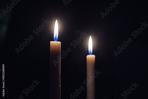 Slika na platnu Two burning candles on a dark background symbolizing remembrance, mourning, hope and spirituality