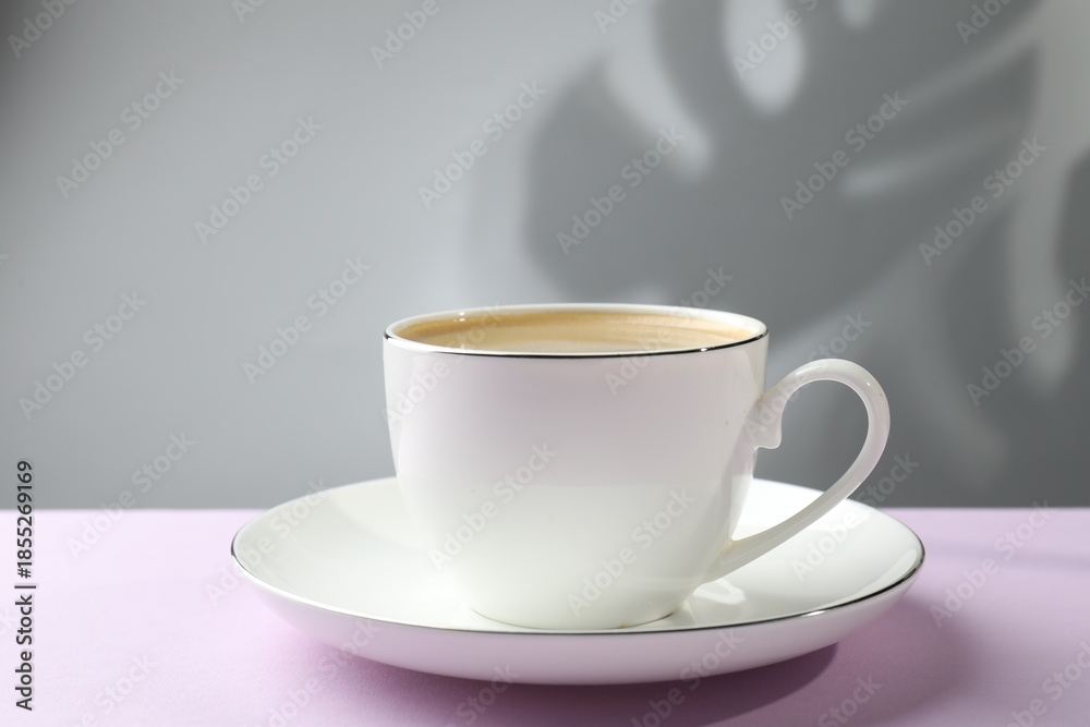 Fototapeta premium Aromatic coffee in cup on violet table, closeup