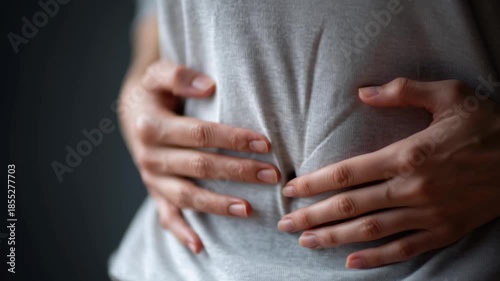 A woman is holding her stomach and her hands are clasped. Concept of discomfort and pain