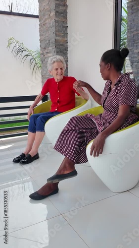 Lilongwe Malawi Africa, 01.12.2025. Video. African female  carer sitting on a patio working with an elderly Dementia sufferer  on holiday in Malawi Africa.