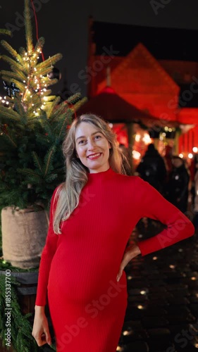 Pregnant Caucasian female enjoying festive outdoor market ambiance with holiday decor and warm lighting slow motion