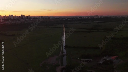 aerial view of a sunrise near Sao Jose dos Campos with a channel and plain field. Beautiful sunrise with orange sky