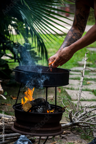 Manos de hombre cocinando al fuego en naturaleza