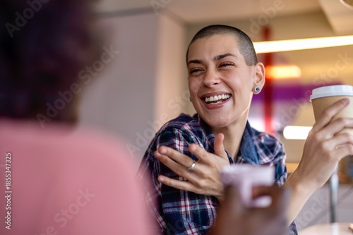 Bilde på lerret Two women laughing heartily together, one holding a coffee cup