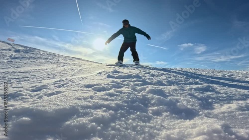 LENS FLARE, CLOSE UP, LOW ANGLE VIEW, SLOW MOTION: Snowboarder crashes and plows into snow while riding down the ski slope. Sparkling ice crystals fly through the air as he tries to stop while sliding
